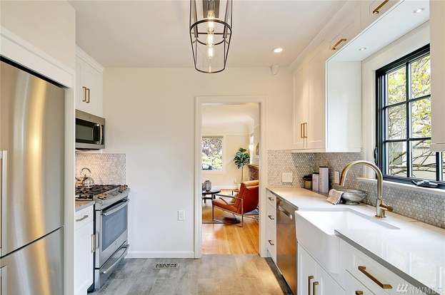 Galley view of Bothell kitchen with stainless gas range, lantern pendant, and pass-through to living room