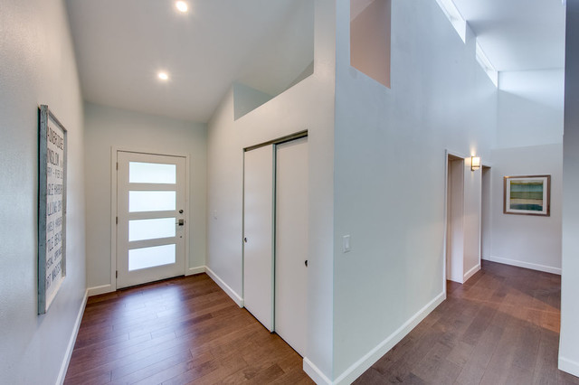 Bright vaulted entry with hardwood floors, modern front door, and clerestory windows