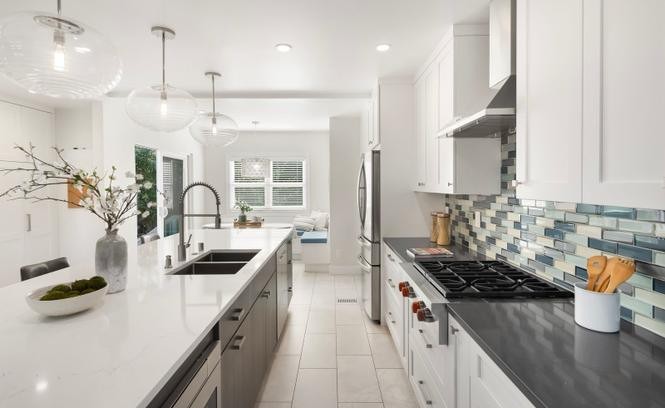 Galley kitchen with blue glass tile backsplash and quartz counters