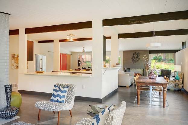 Open living and dining area with exposed beams and pass-through to kitchen
