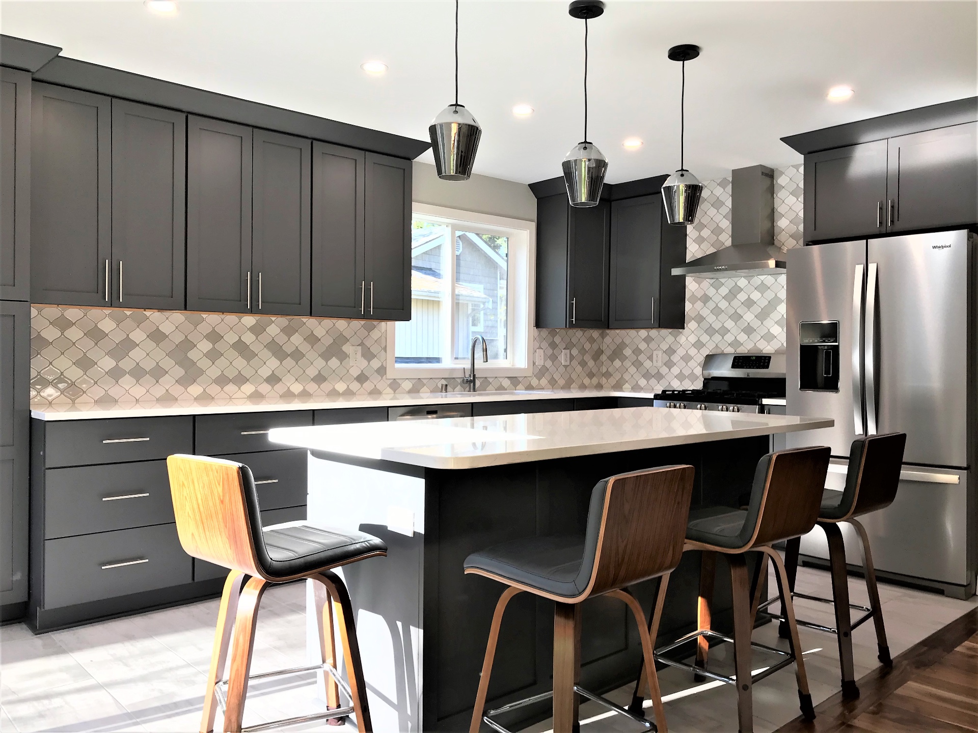 Snohomish County kitchen remodel with charcoal shaker cabinetry, arabesque tile backsplash, quartz waterfall island, and smoked glass pendants