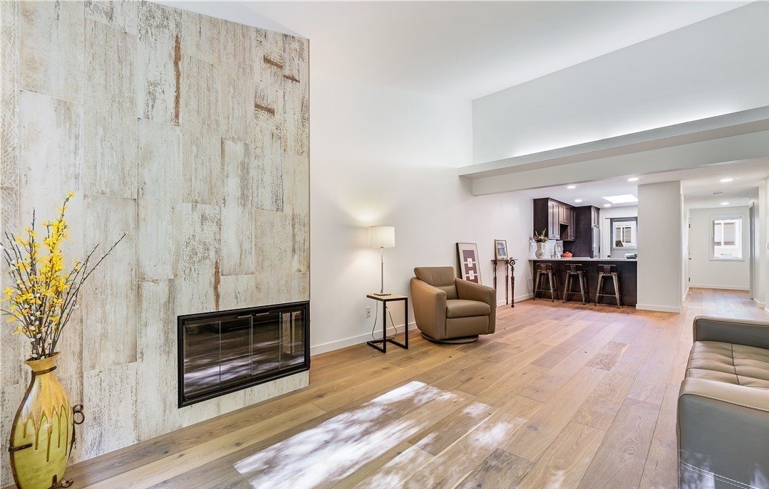 Vaulted living room with whitewashed wood-tile fireplace wall and wide-plank oak floors