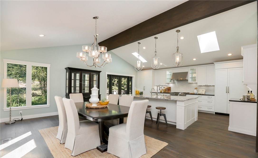 Open dining and kitchen with vaulted ceiling, beams, and chandelier