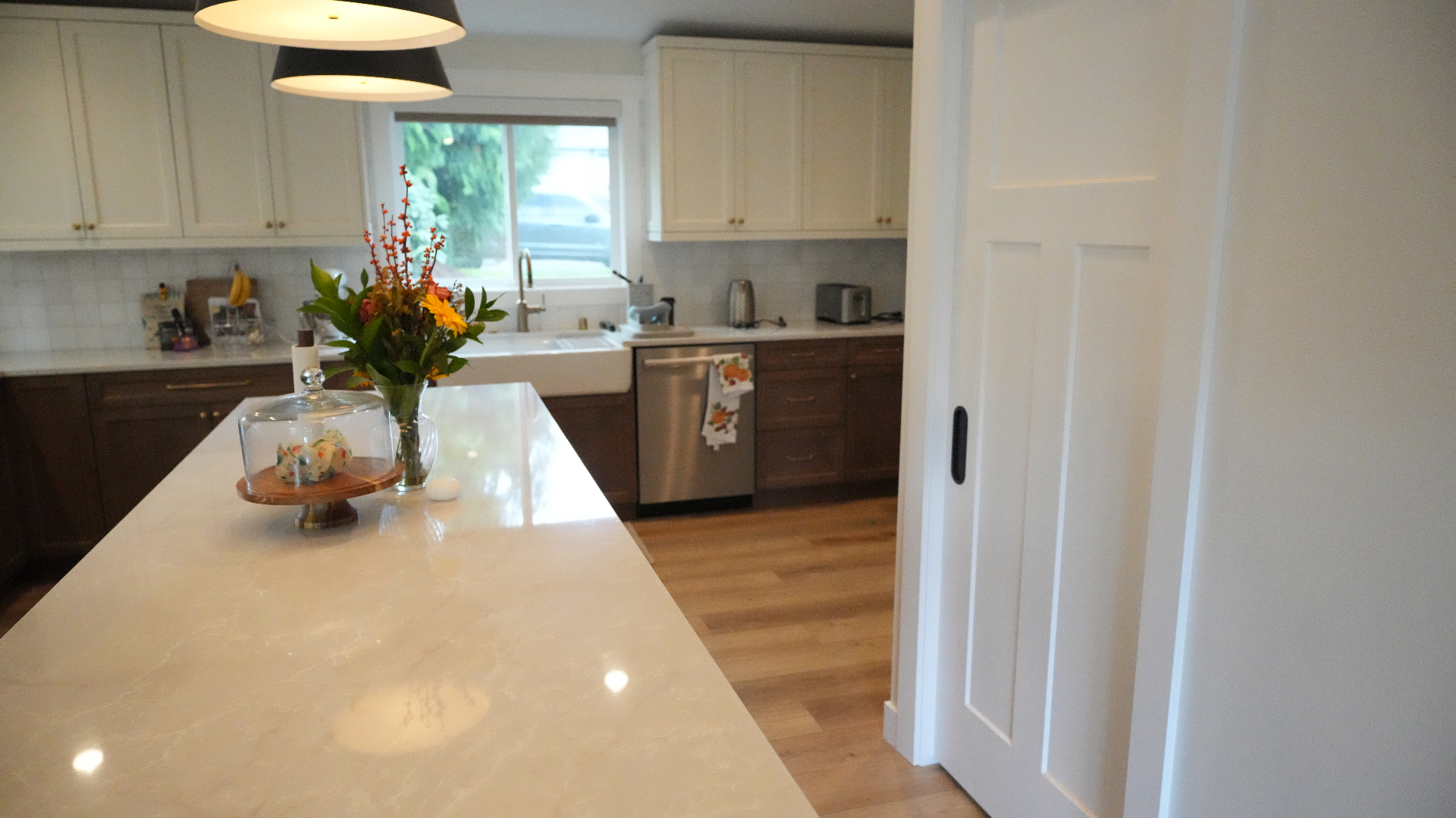 Quartz island view toward sliding pantry door and sink wall in Bellevue kitchen