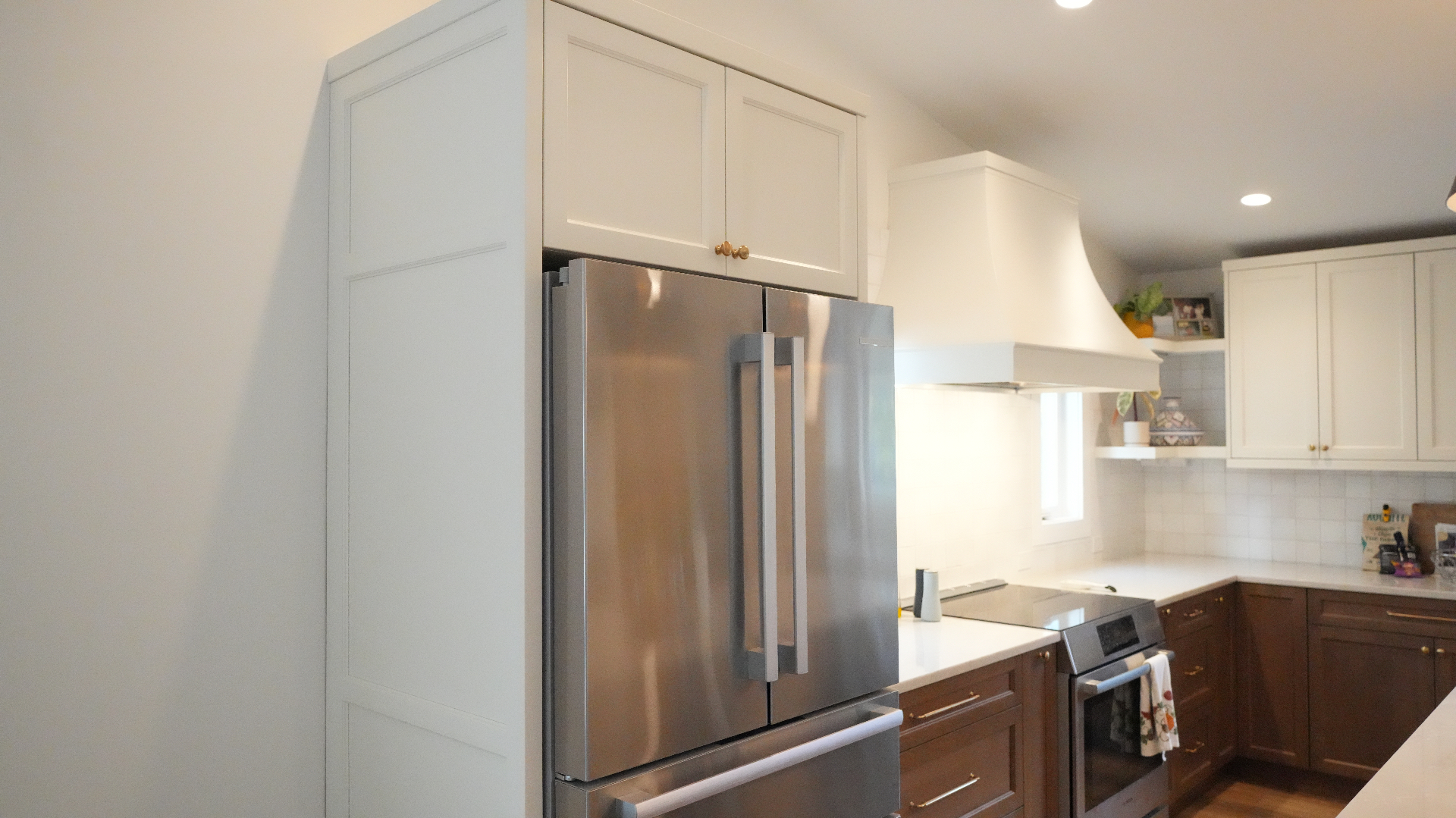 Built-in stainless French-door refrigerator framed by white Shaker cabinets
