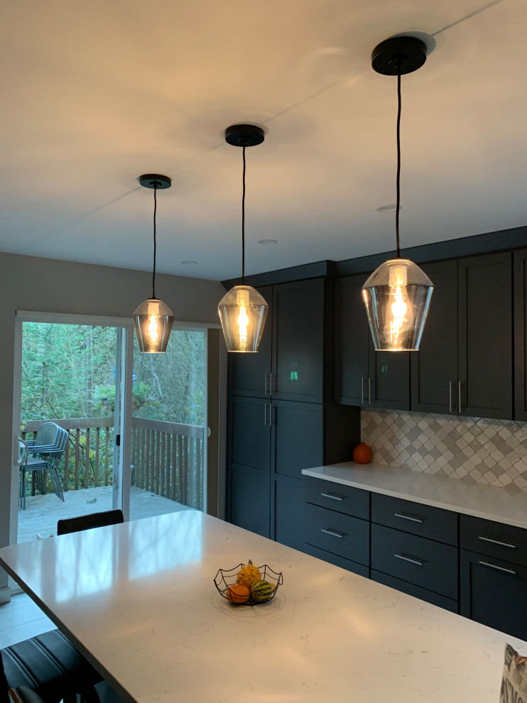 Three smoked-glass pendants hanging over quartz island at dusk