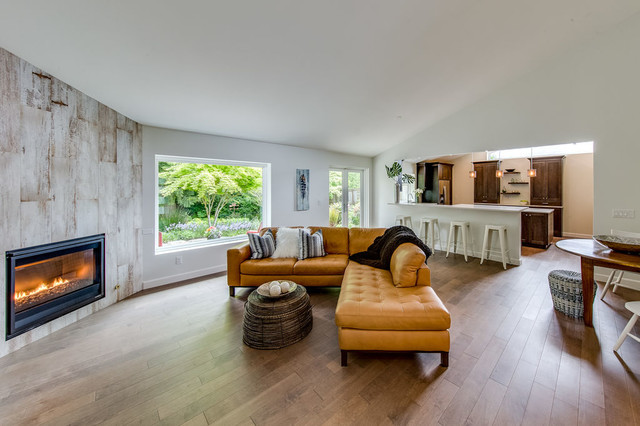 Great room with leather sectional, reclaimed-wood fireplace wall, and open view into kitchen