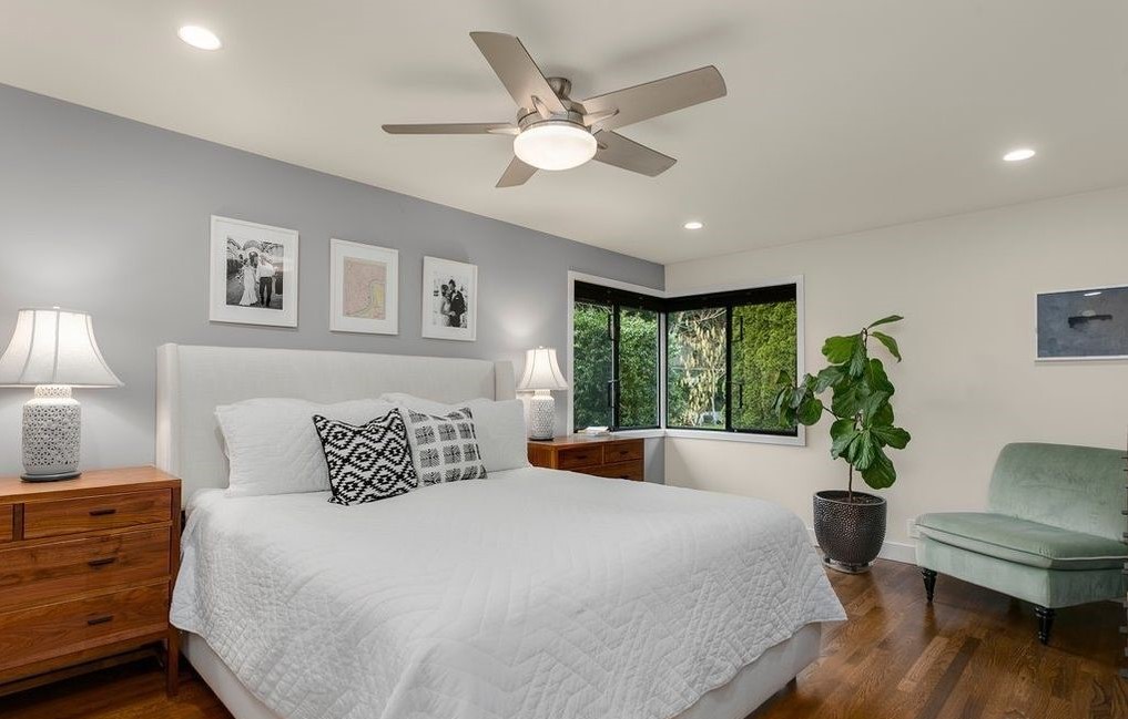 Primary suite with hardwood floors, oversized windows, and custom millwork