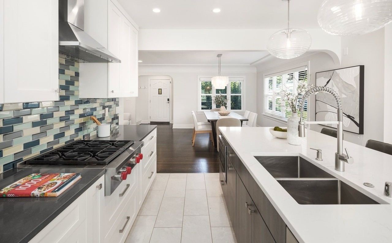 Chef's kitchen with gas cooktop, quartz island, and dual sinks open to dining
