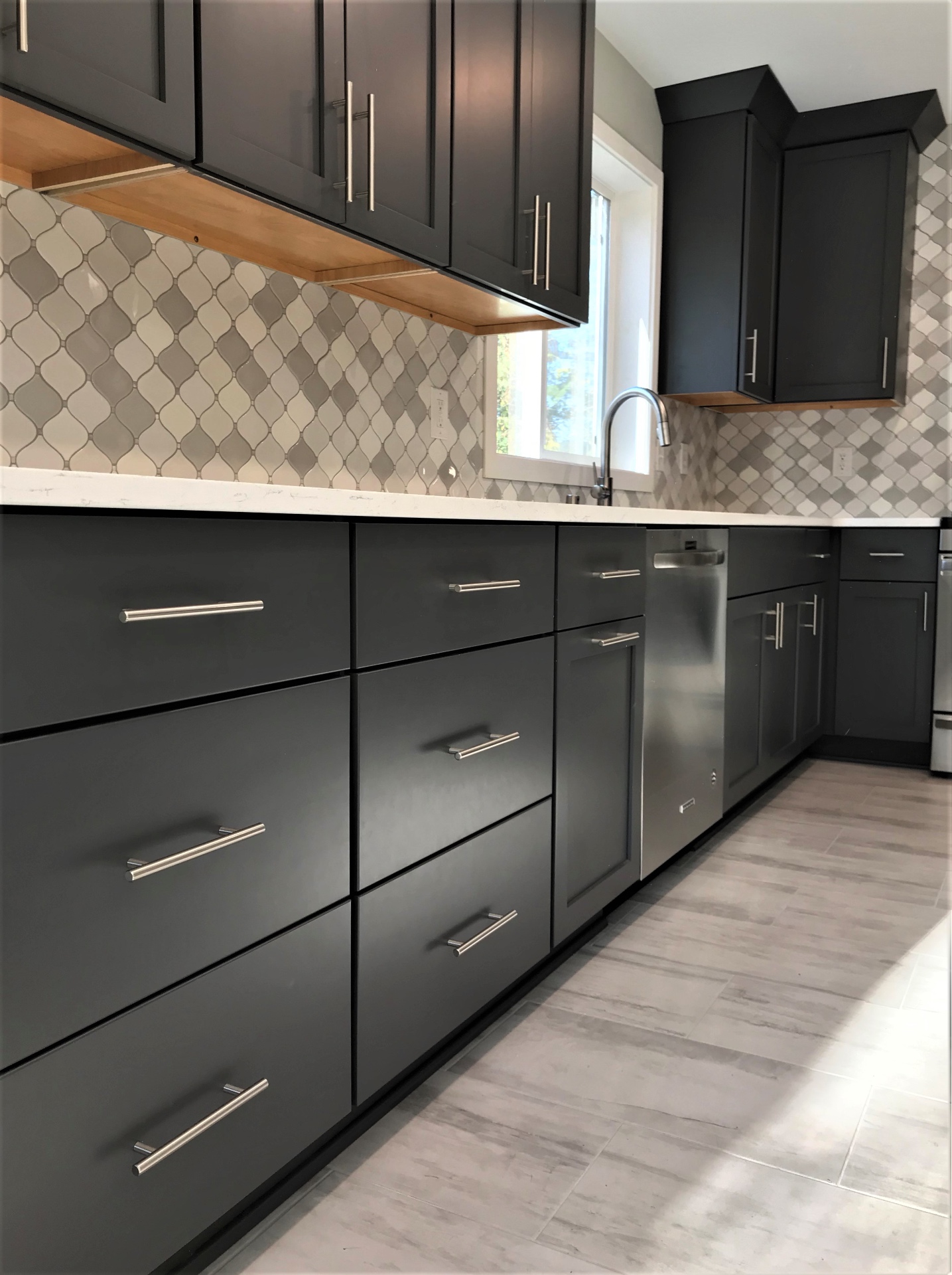 Charcoal cabinetry detail with brushed nickel bar pulls, quartz counters, and tile floor