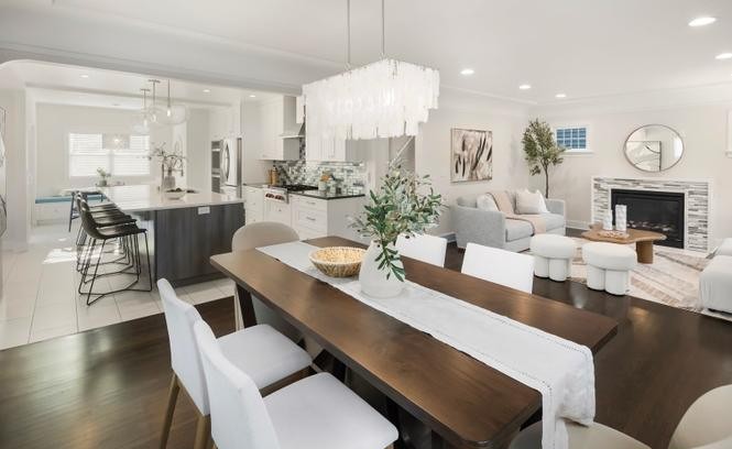 Open-concept living, dining, and kitchen with fireplace and waterfall chandelier