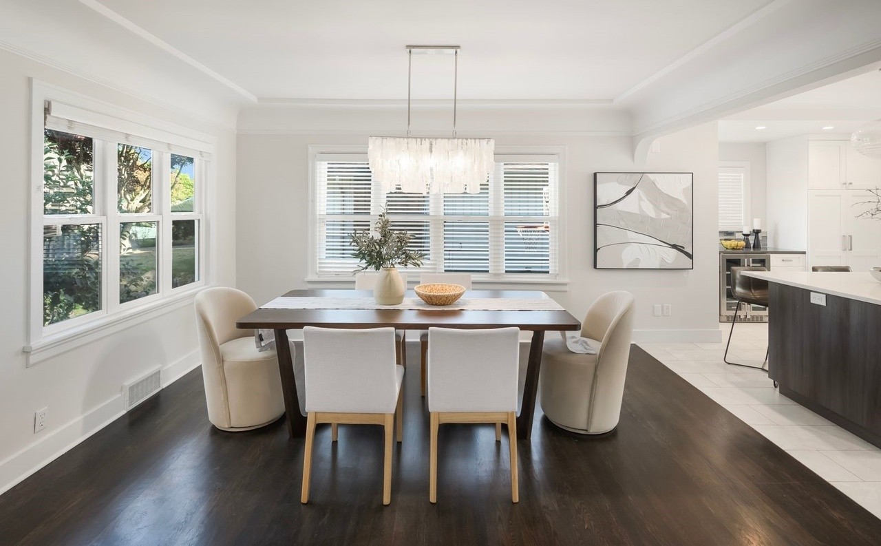 Formal dining room with tray ceiling, dark hardwood, and statement chandelier