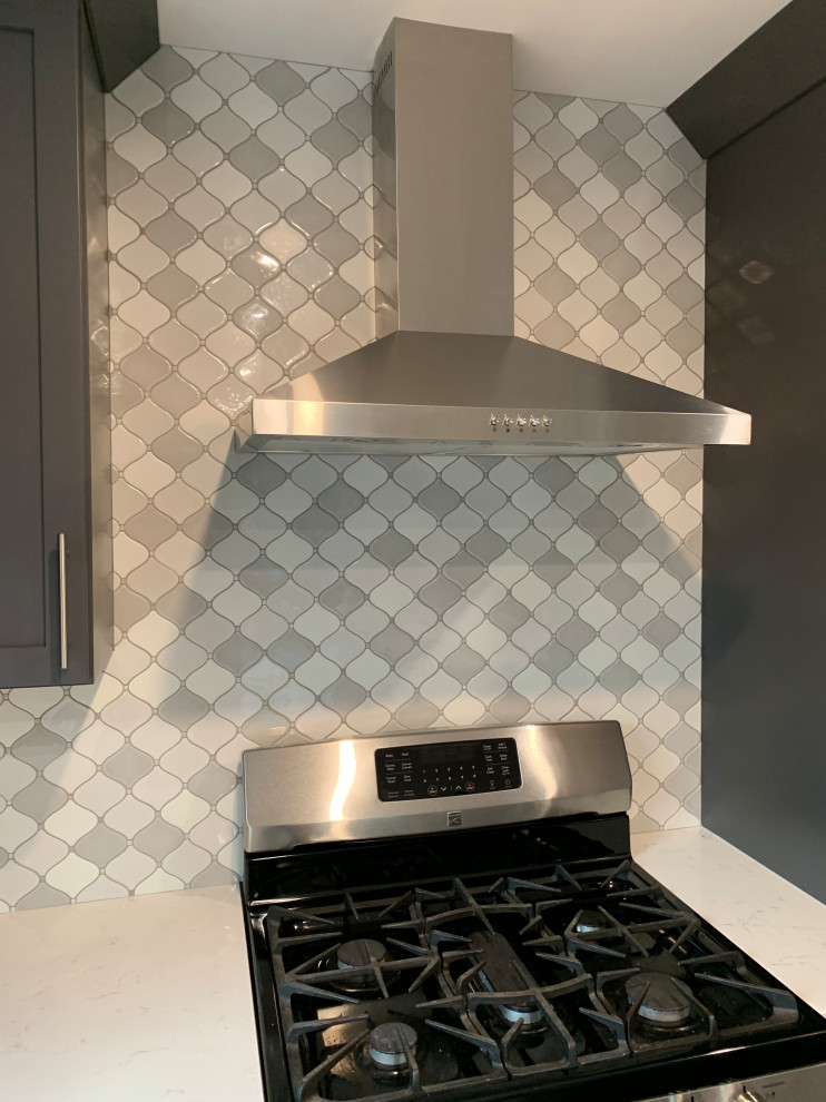 Stainless chimney hood over gas range with arabesque tile backsplash
