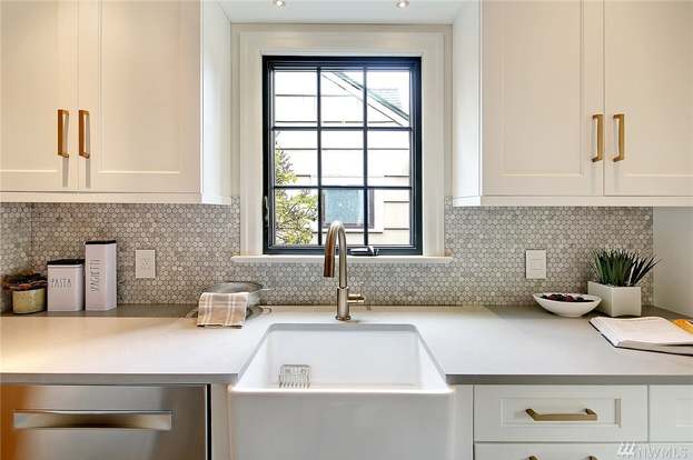 Close-up of farmhouse sink, bridge faucet, penny-round tile, and steel-framed window in Bothell kitchen