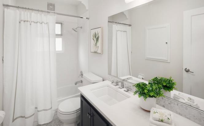 Guest bath with tub-shower combo, white vanity, and quartz counter
