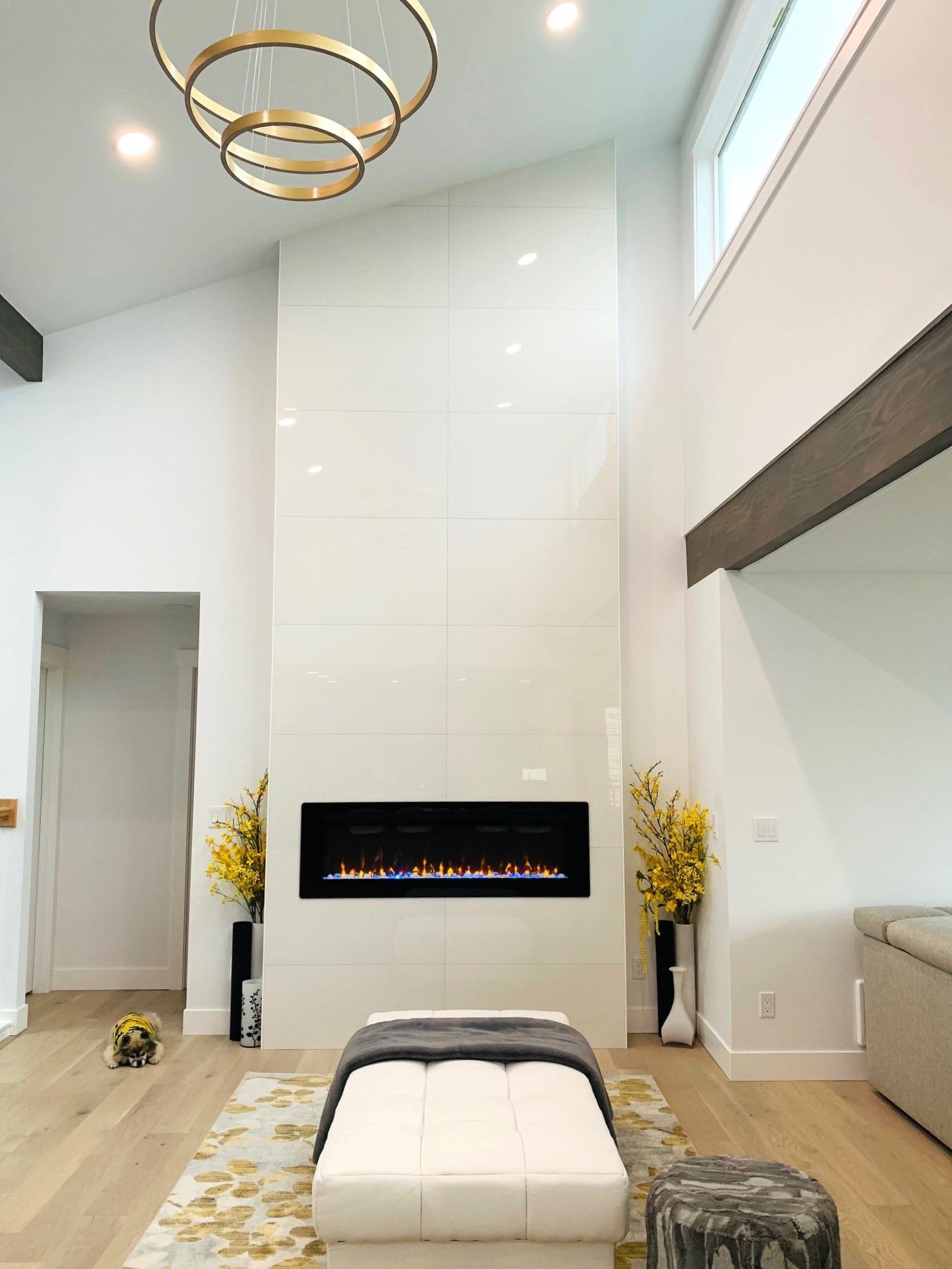Two-story fireplace wall with electric insert, brass chandelier, and vaulted ceiling