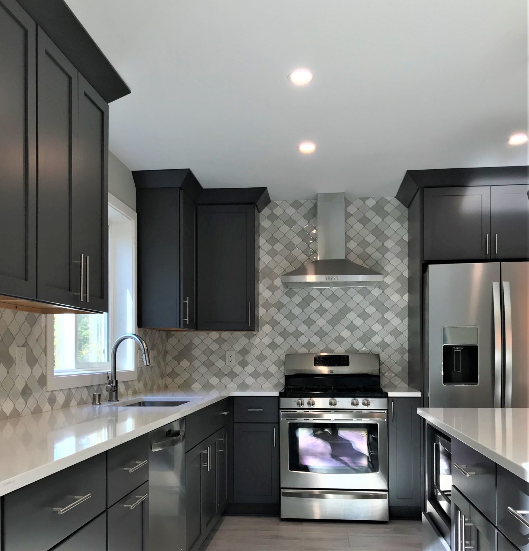 Cook wall with stainless gas range, chimney hood, and full-height arabesque mosaic backsplash